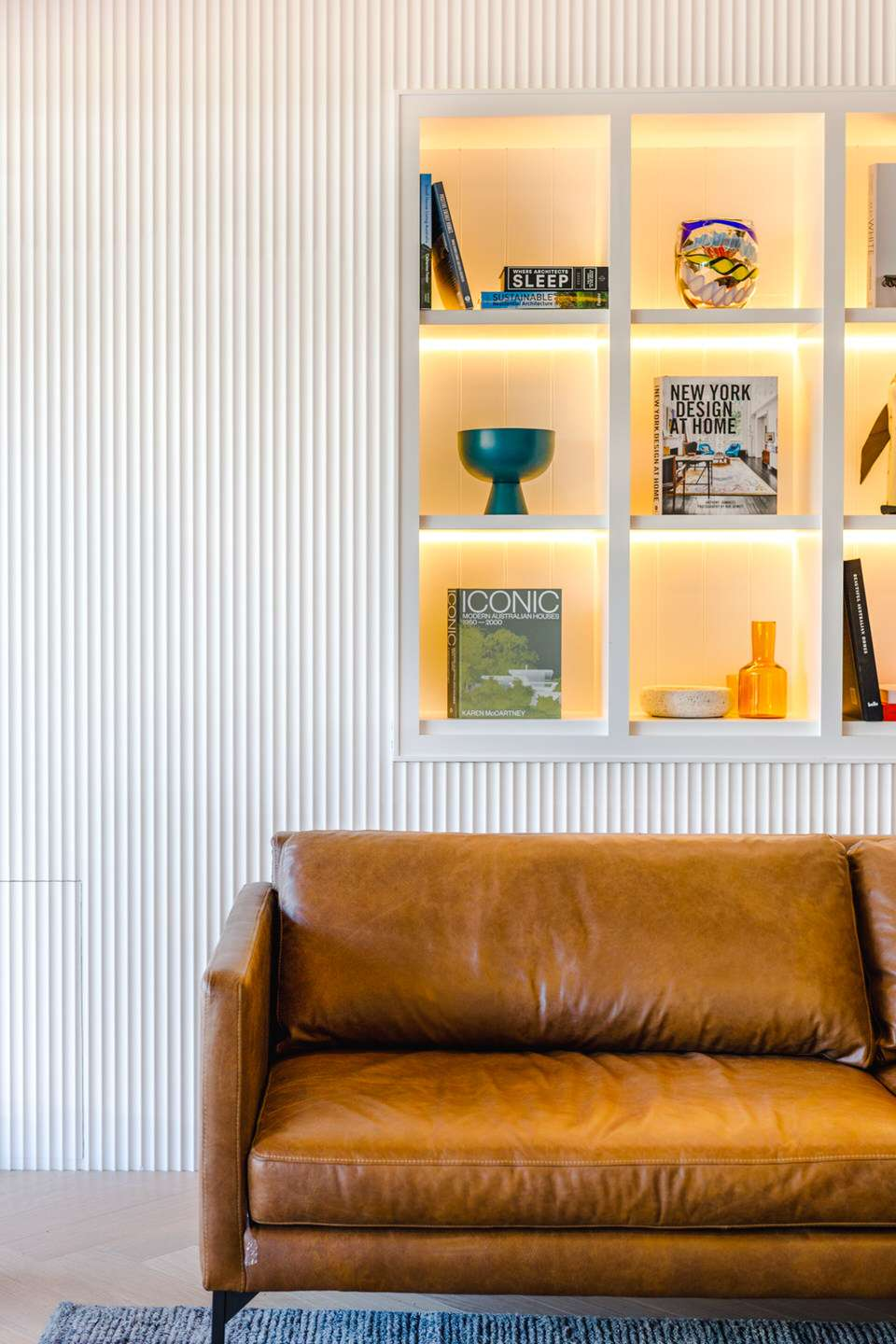 Warmly lit interior with brown leather sofa and display shelving